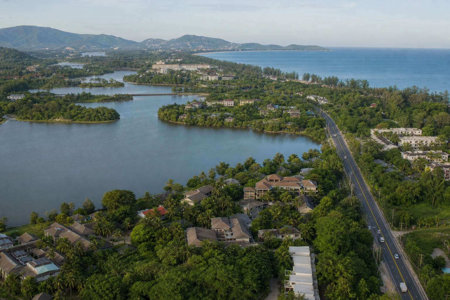 AI-generated aerial editorial view of a green Phuket coastal area with lagoons, low-rise buildings and a connecting road